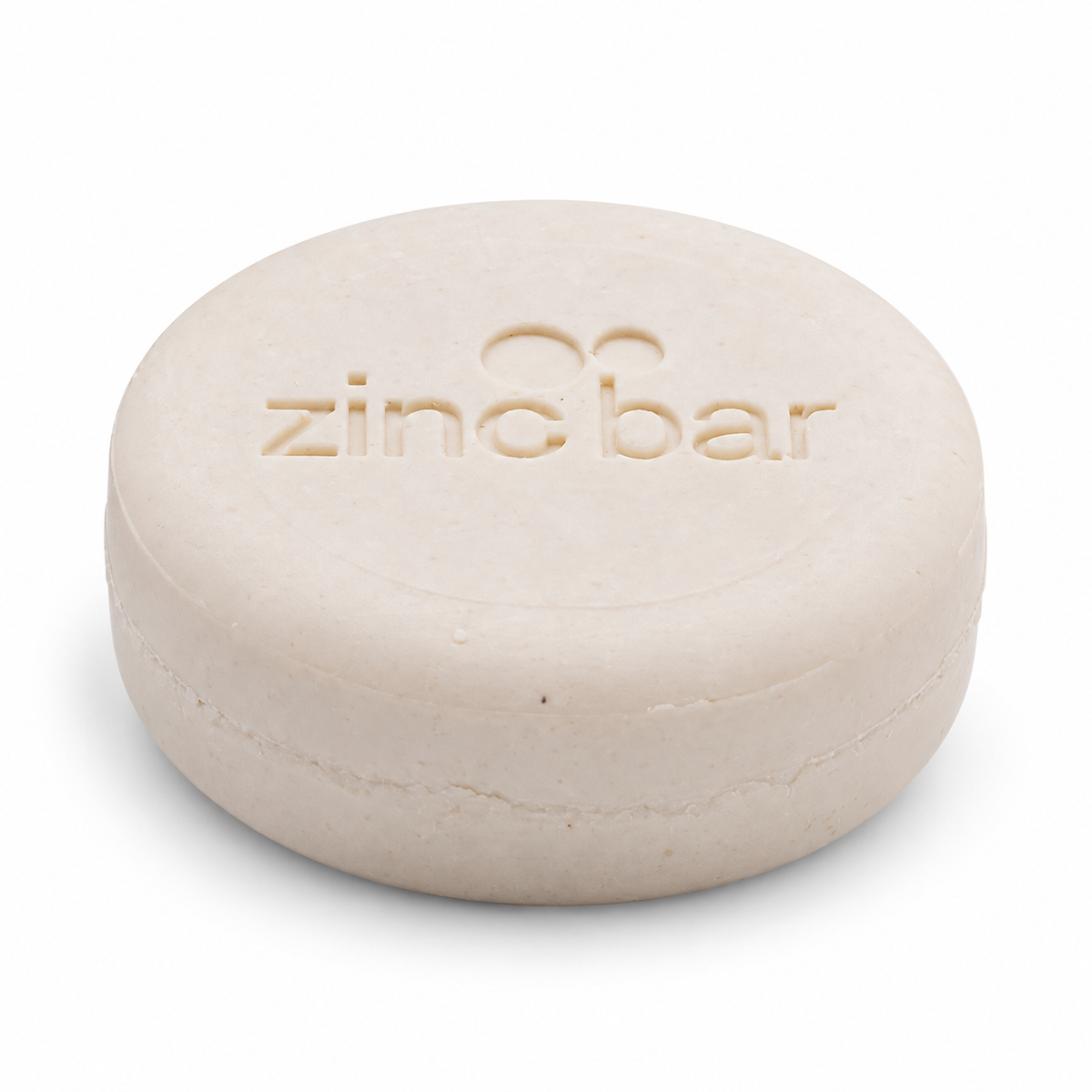 DermaHarmony Zinc Shampoo Bar 2% Pyrithione Zinc Tea Tree 113 g - A round beige zinc soap bar with embossed text